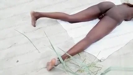 Ebony girl masturbates in the sand while being filmed
