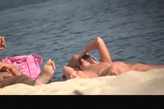 Nude woman in nudist beach sunbathing
