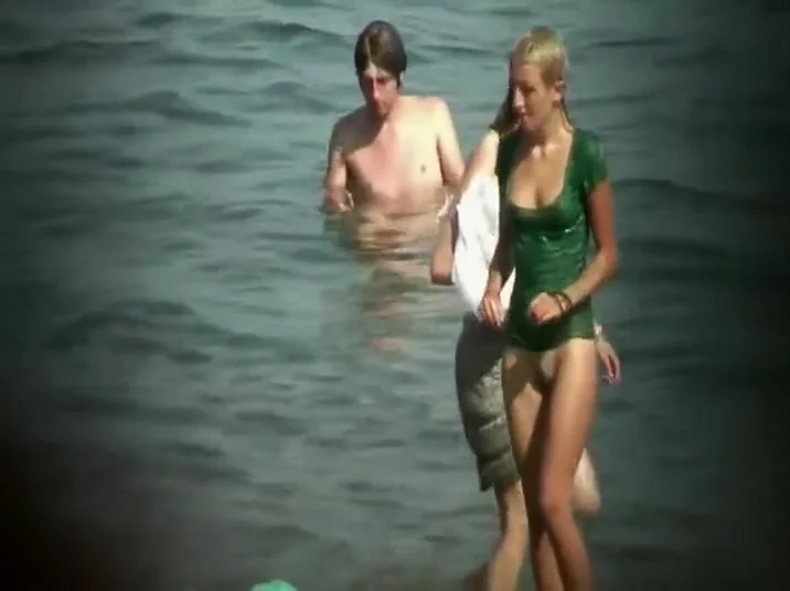Nudist girl washes a towel in the water