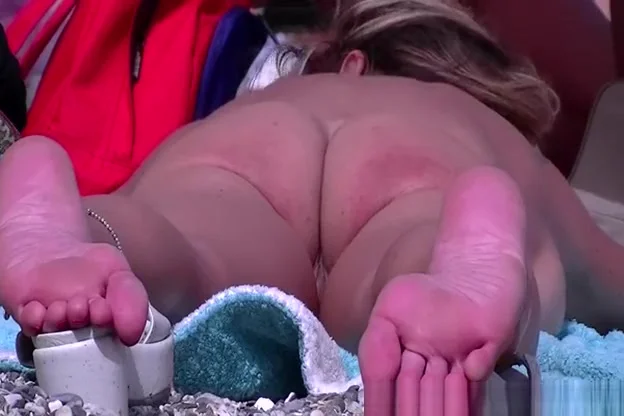 Nudist woman laid down on her belly sunbathing
