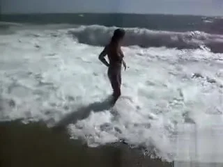Busty brunette's lower of a bikini drops as huge waves hit her