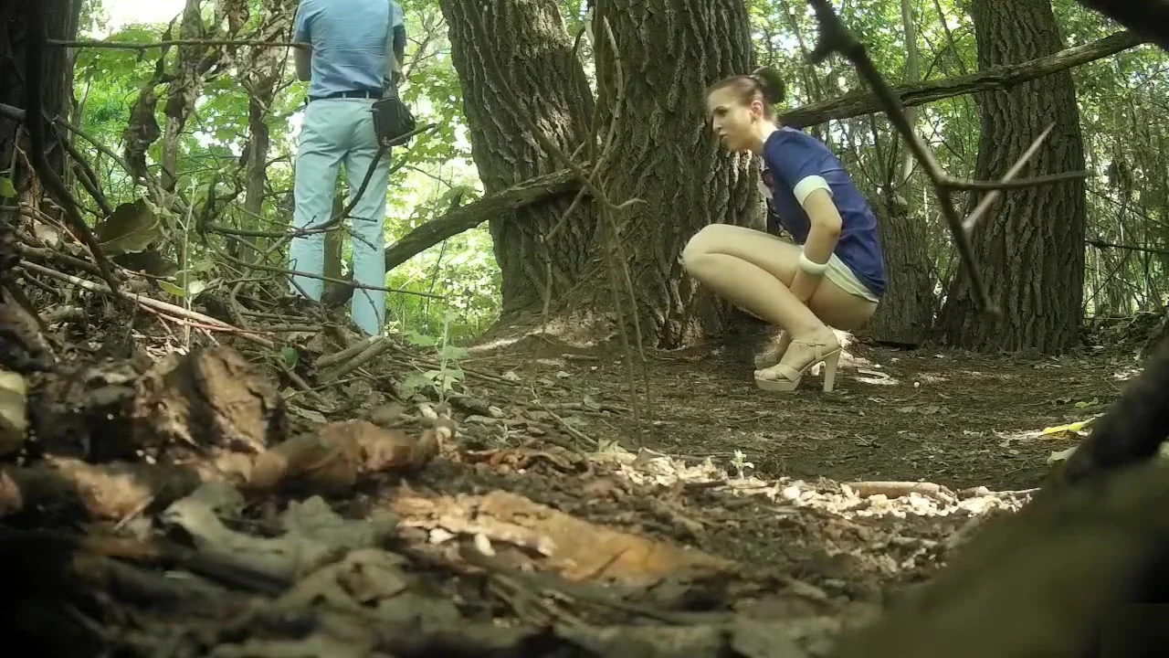 Guy stands on guard as his girlfriend pees behind a tree