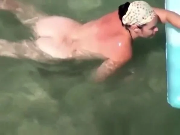 Nudist woman swimming in the beach