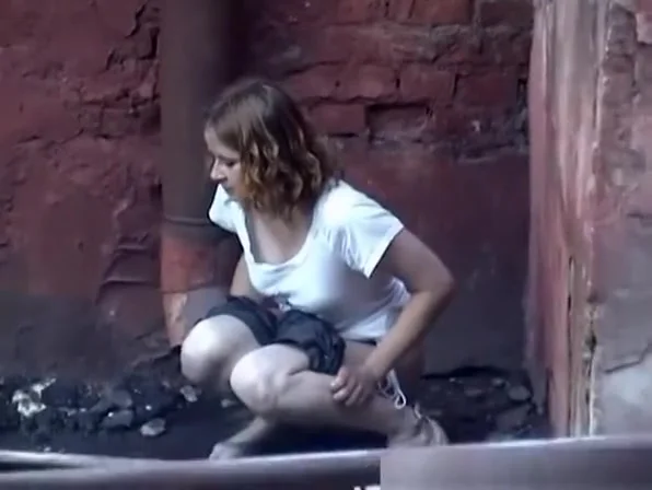 Girl pees in public next to old buildind