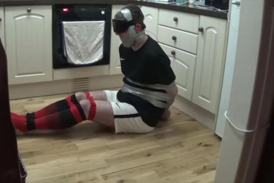 Footballer tied and taped tight on kitchen floor