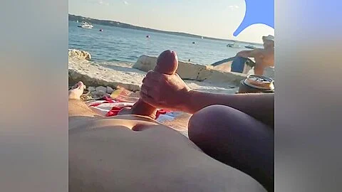 On a nude beach the wife stokes my cock while a voyuer watches