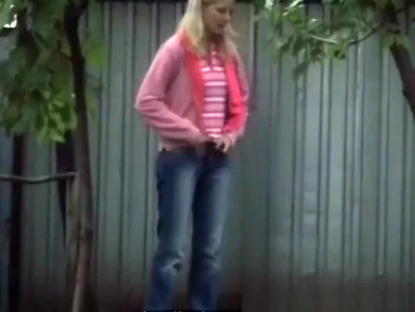 Blonde girl in tight jeans pants peeing outdoors