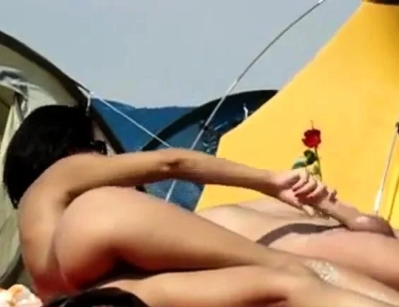 Brunette gives a handjob on a nudist beach