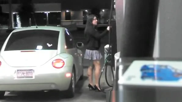 Short skirt girl putting gas in car