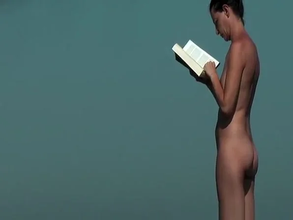 Nudist woman reading book in the beach