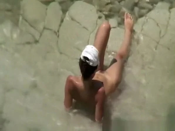 Two nudist women laid down by the water
