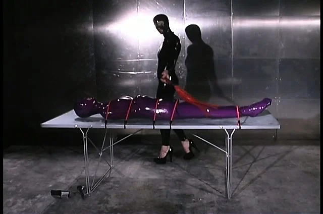 Latex slave gets bound to a table and beaten by her sexy mistress