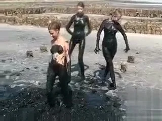 Young ladies coat their bodies in dark mud