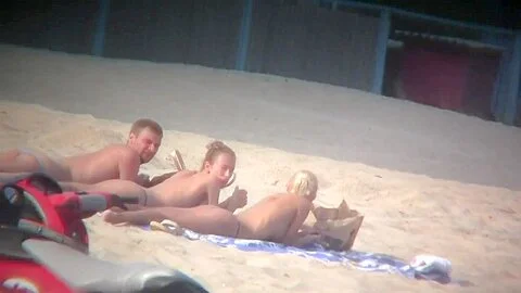 Thrilling nude friends are relaxing on a nudist beach