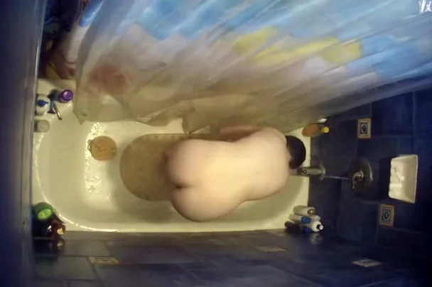 Nude woman bending over in bathtub